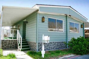 A blue colored wooden house with stairs and lawn